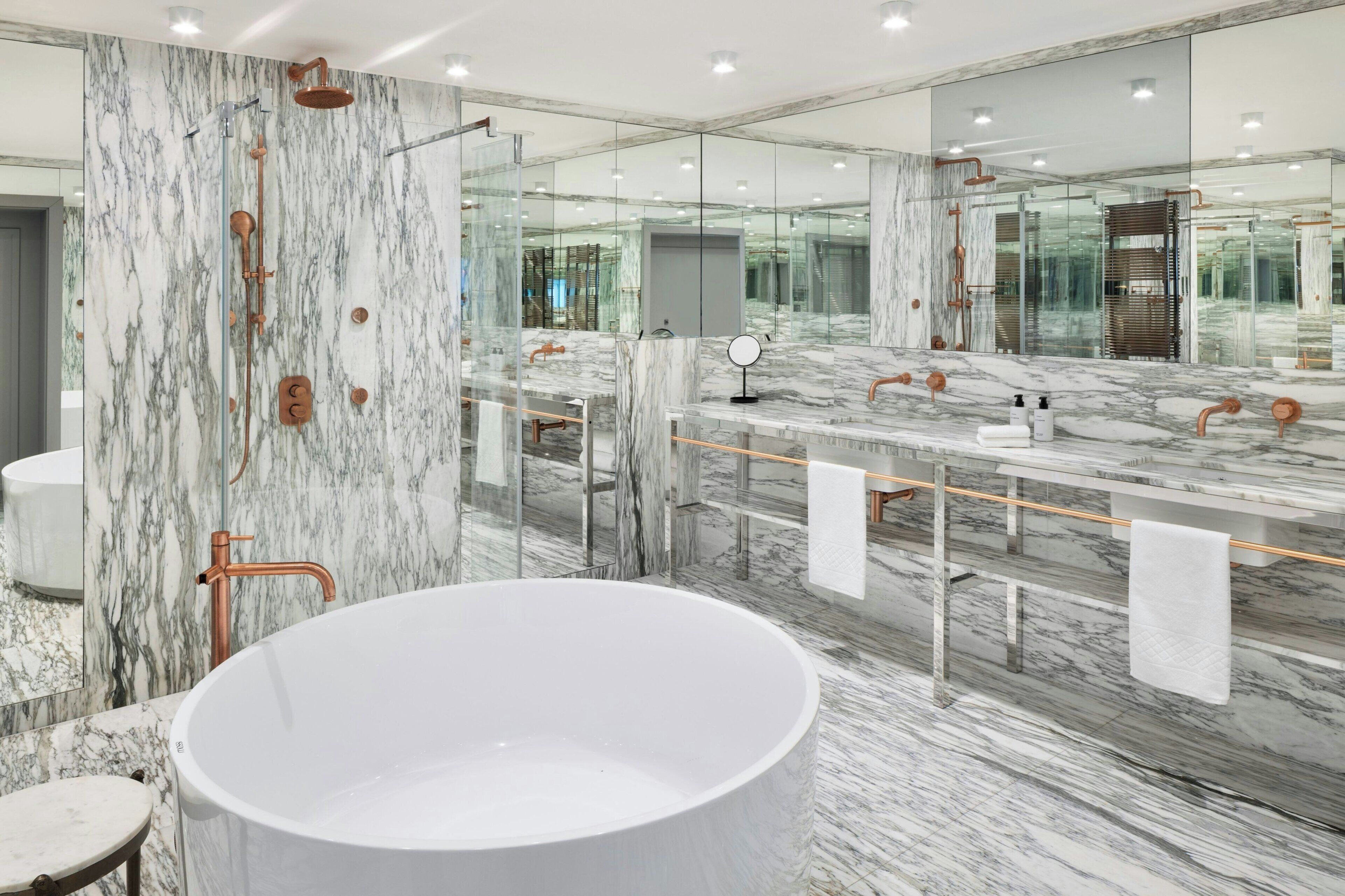 A modern bathroom with a large freestanding bathtub, a glass-enclosed shower, and a marble-topped vanity with a mirror.