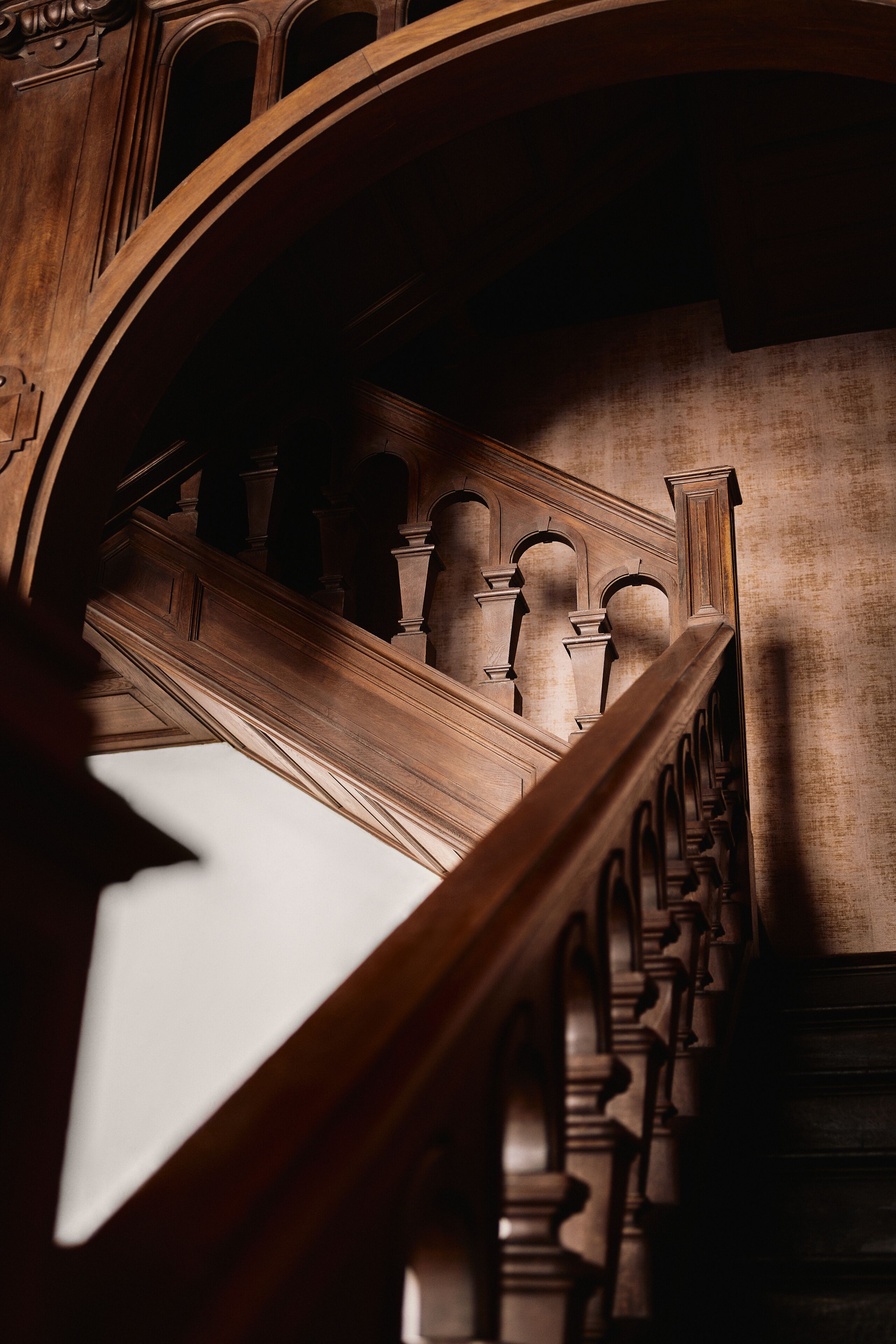 A grand staircase with ornate wooden railings and a vaulted ceiling.