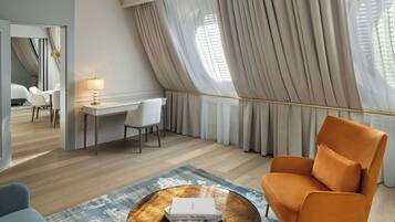 A modern hotel room with a desk, chair, and a large window with curtains.