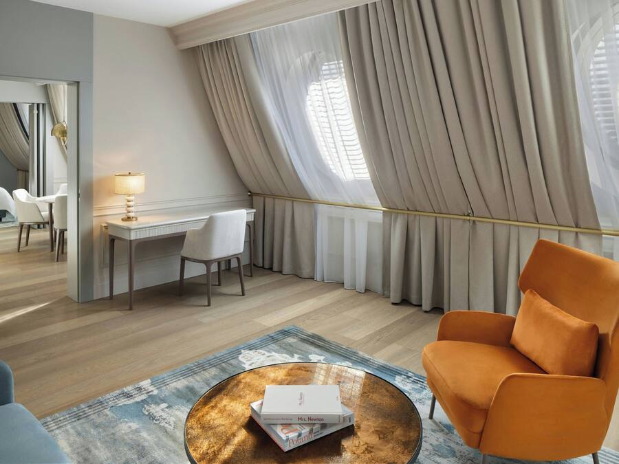 A modern hotel room with a desk, chair, and a large window with curtains.