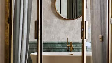 Un baño con bañera, un espejo redondo y suelo de mármol.