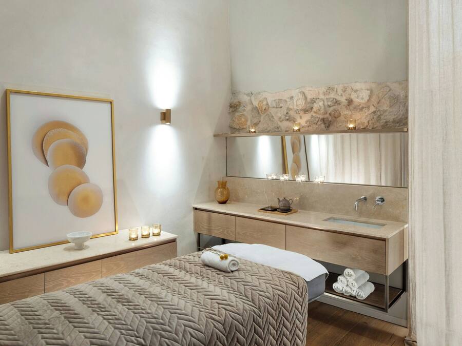 A modern bathroom with a large mirror, a sink, and a bed.
