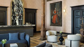 A lobby with a marble reception desk, a large painting, a sofa, armchairs, and a coffee table.