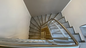 A modern staircase with a metal handrail and a circular light fixture at the top. - Signature East Hotel Falk (Hamburg)