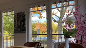 A dining area with a wooden table, a white vase with flowers, and a metal bowl. - Signature East Hotel Falk (Hamburg)