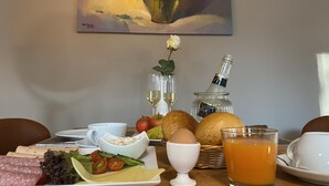 A breakfast setting with a variety of food items, a bottle of champagne, and a painting on the wall. - Signature East Hotel Falk (Hamburg)