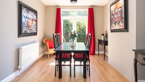 Een eetkamer met een tafel, stoelen en kunstwerken aan de muur.