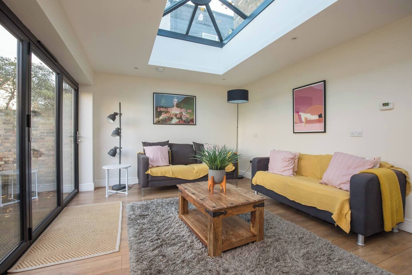 Un salon moderne doté d’une verrière, de deux canapés, d  ’une table basse et d’un lampadaire.
