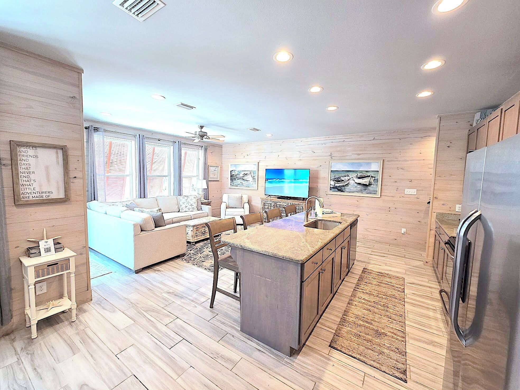 A modern kitchen with a central island, wooden cabinetry, and a built-in refrigerator.