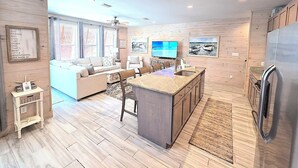 Een moderne keuken met een centraal eiland, houten kastjes en een geïntegreerde koelkast.