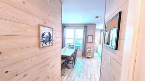 Een houten interieur met een eethoek, ingelijste kunstwerken en uitzicht door een raam.