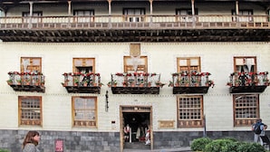 Ein traditionelles Gebäude mit mehreren Balkonen, die mit Blumenkästen geschmückt sind, einem zentralen Eingang und einer Flagge auf dem Dach.