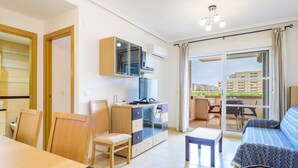 Eine moderne Wohnung mit Essbereich, Küchenzeile und einem Balkon mit Stadtblick.