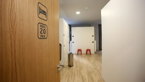 A hotel corridor with a wooden door, a trash bin, and two red stools. - dpaso Urban Hostel (Pontevedra)