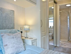 A bedroom with a bed, a bedside table with a lamp, and a view into the bathroom. - 2 bedroom accommodation in Lanlivery (Lanlivery)
