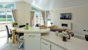 Amplia sala de estar con un gran ventanal, un televisor de pantalla plana, una mesa de comedor con sillas y un sofá.