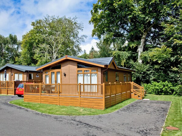 A wooden cabin with a porch and a car parked in front. - 2 bedroom accommodation in Lanlivery (Lanlivery)