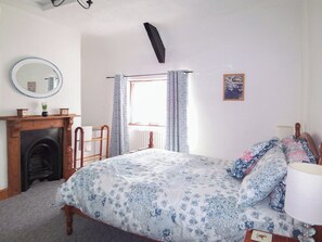 A bedroom with a bed, a wooden dresser, a mirror, a fireplace, and a window with curtains. - 2 bedroom accommodation in Wells (Wells)