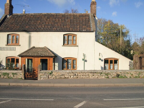 A two-story building with a sloped roof, stone foundation, and multiple windows with wooden frames. - 2 bedroom accommodation in Wells (Wells)
