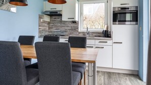 Una cucina moderna con mobili bianchi, forno integrato e una finestra vista alberi.