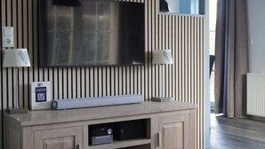 Un soggiorno moderno con una TV a schermo piatto montata su una parete con listelli in legno verticale, un impianto audio integrato e un tavolino con una lampada.