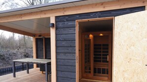 Un patio in legno con tavolo e sedie, una zona coperta e una porta d'ingresso.