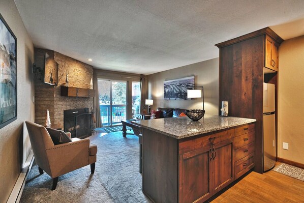A spacious kitchen with a large island, dark wood cabinetry, and a view to a balcony. - Mountain Views! Hot Tub/Pool Walk to Lifts & Main3 (Park City)