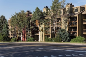 Un edificio residencial de varios pisos con balcones, rodeado de árboles.