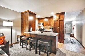 A modern kitchen with wooden cabinets, a granite countertop, and a bar area with stools.