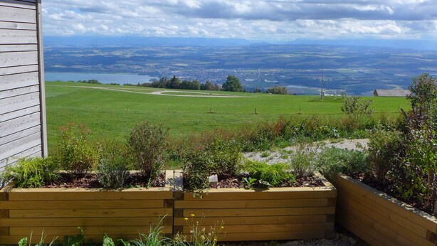 A view from a wooden cabin overlooking a green field and a distant town. - Stunning private villa for 6 people with WIFI, pets allowed and panoramic view (Les Cluds)