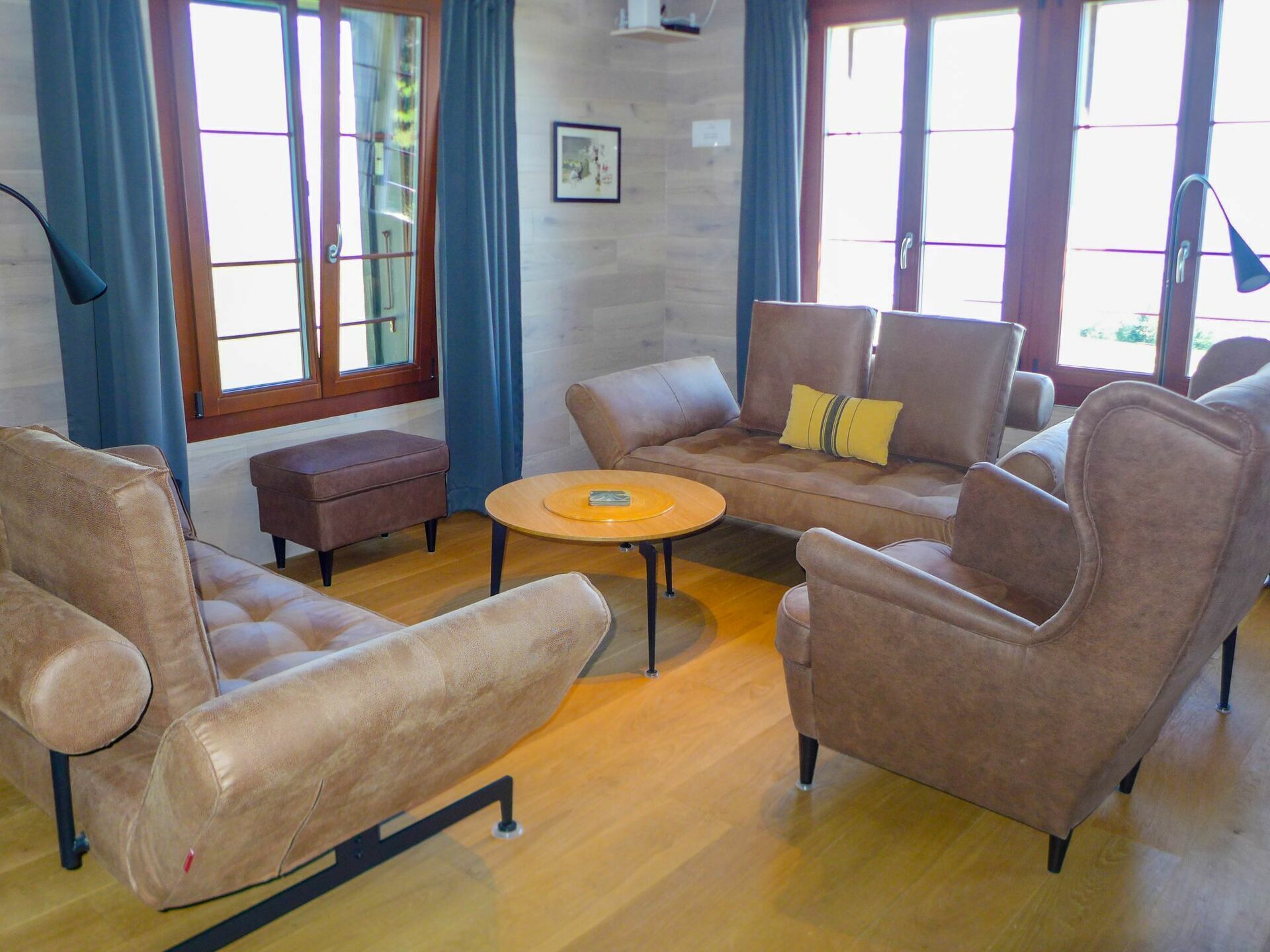 Un salon avec un canapé marron, une petite table ronde et un plancher en bois.