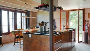 A modern kitchen with a central island, wooden cabinetry, and large windows. - Stunning private villa for 6 people with WIFI, pets allowed and panoramic view (Les Cluds)