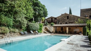 Una piscina amb gandules, una escala de pedra i edificis tradicionals al fons.