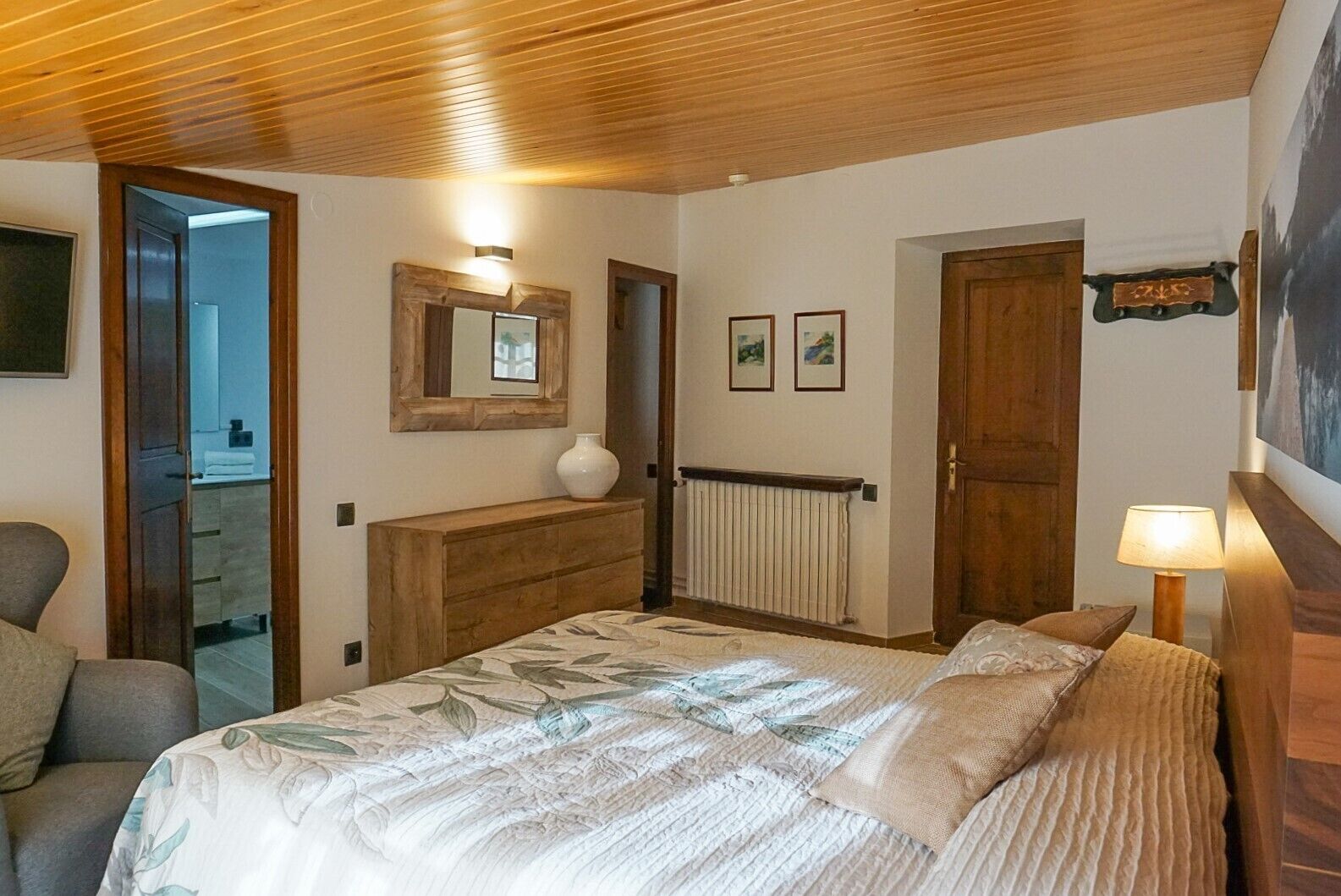 A bedroom with a bed, a dresser, a mirror, a radiator, and a door.