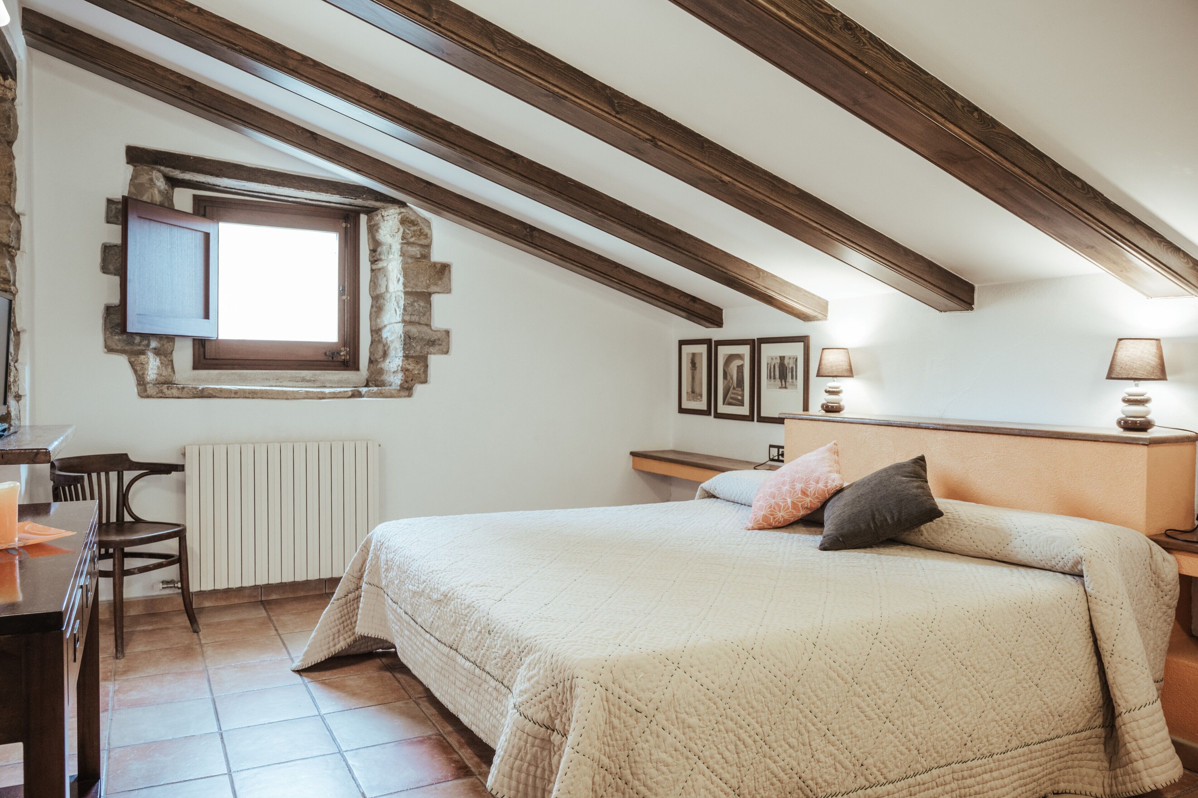 A bedroom with a large bed, a desk, and a window with a view.