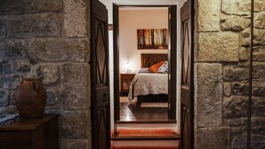 Passadís estret que condueix a un dormitori amb un llit, una taula de nit i un quadre a la paret.