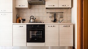 Een moderne keuken met lichte houten kastjes, een zwarte oven en een roestvrijstalen afzuigkap.