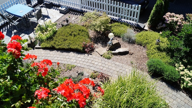 A garden with a paved pathway, a white picket fence, and a table with chairs. - Gästehaus Panorama (Bruttig-Fankel)