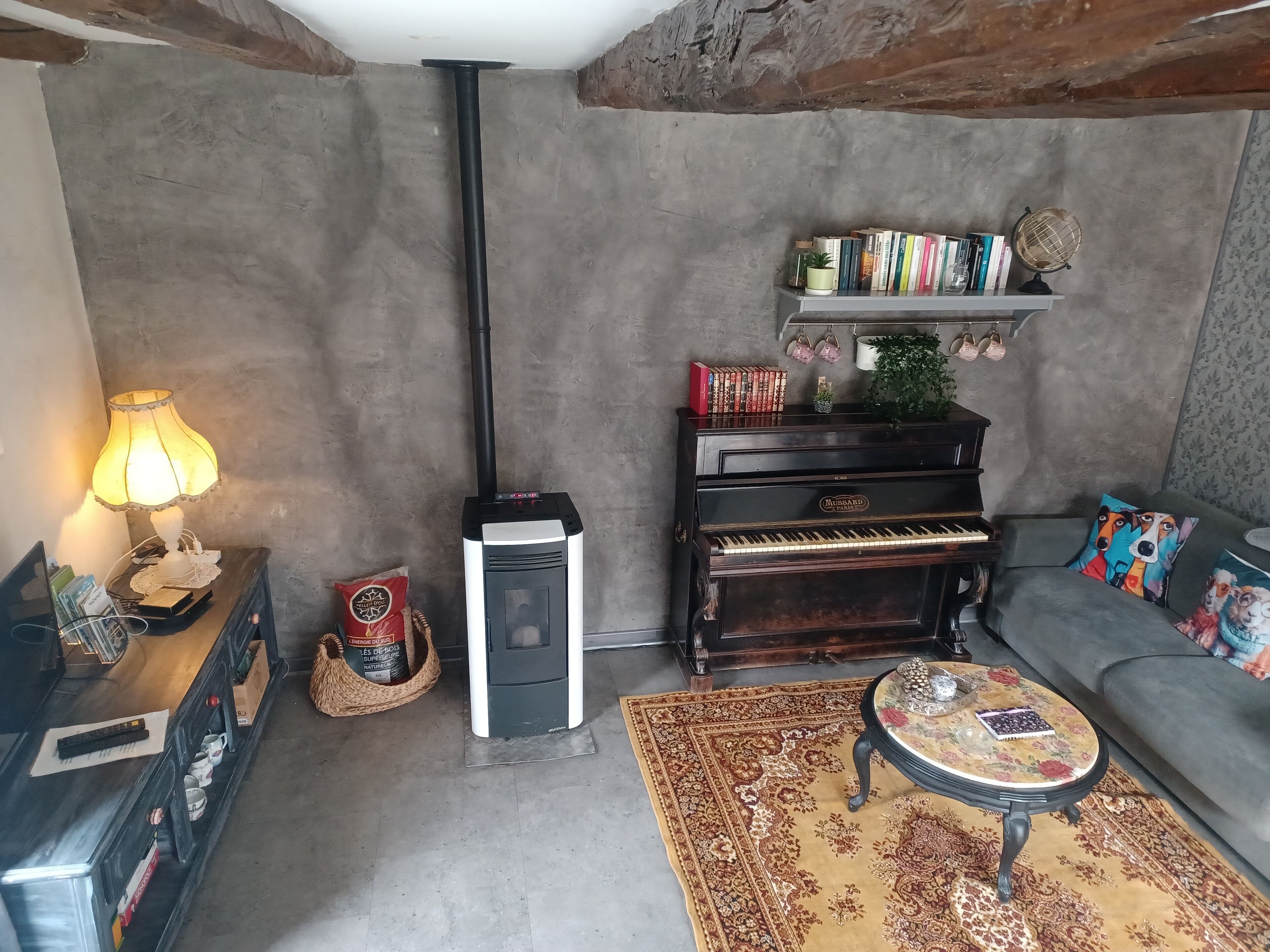 En hyggelig stue med et klaver, en lampe, et tæppe og en sofa.