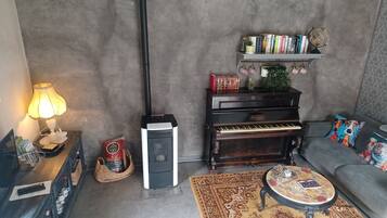 En hyggelig stue med et klaver, en lampe, et tæppe og en sofa.