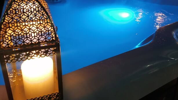 A hot tub with a blue light, a candle, and a decorative lantern. - Country cottage Le Mas with jacuzzi (Brassac)