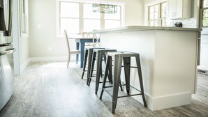 Une cuisine moderne dotée d’un îlot central, de tabourets de bar et d’un coin repas avec des chaises.