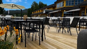 Un patio al aire libre con piso de madera, sillas y mesas de metal negro.