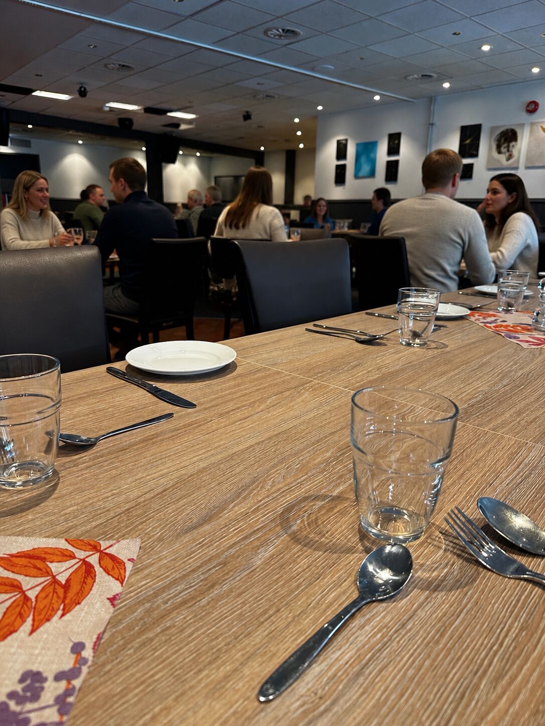 Interior de restaurante com mesas postas para refeições, incluindo talheres e copos.