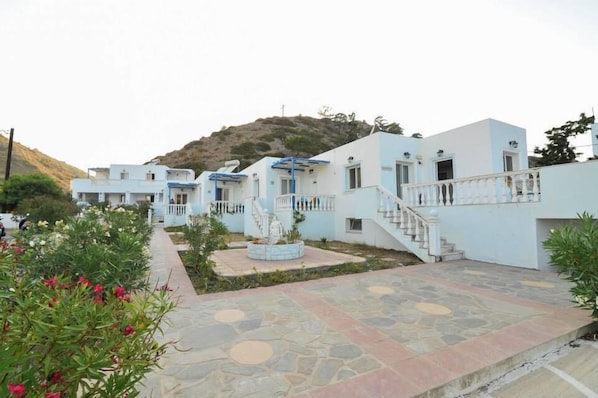 A row of white buildings with blue accents, a central staircase, and a landscaped garden area.