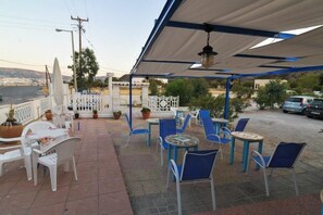 An outdoor patio with white and blue chairs, tables, and a white fence.