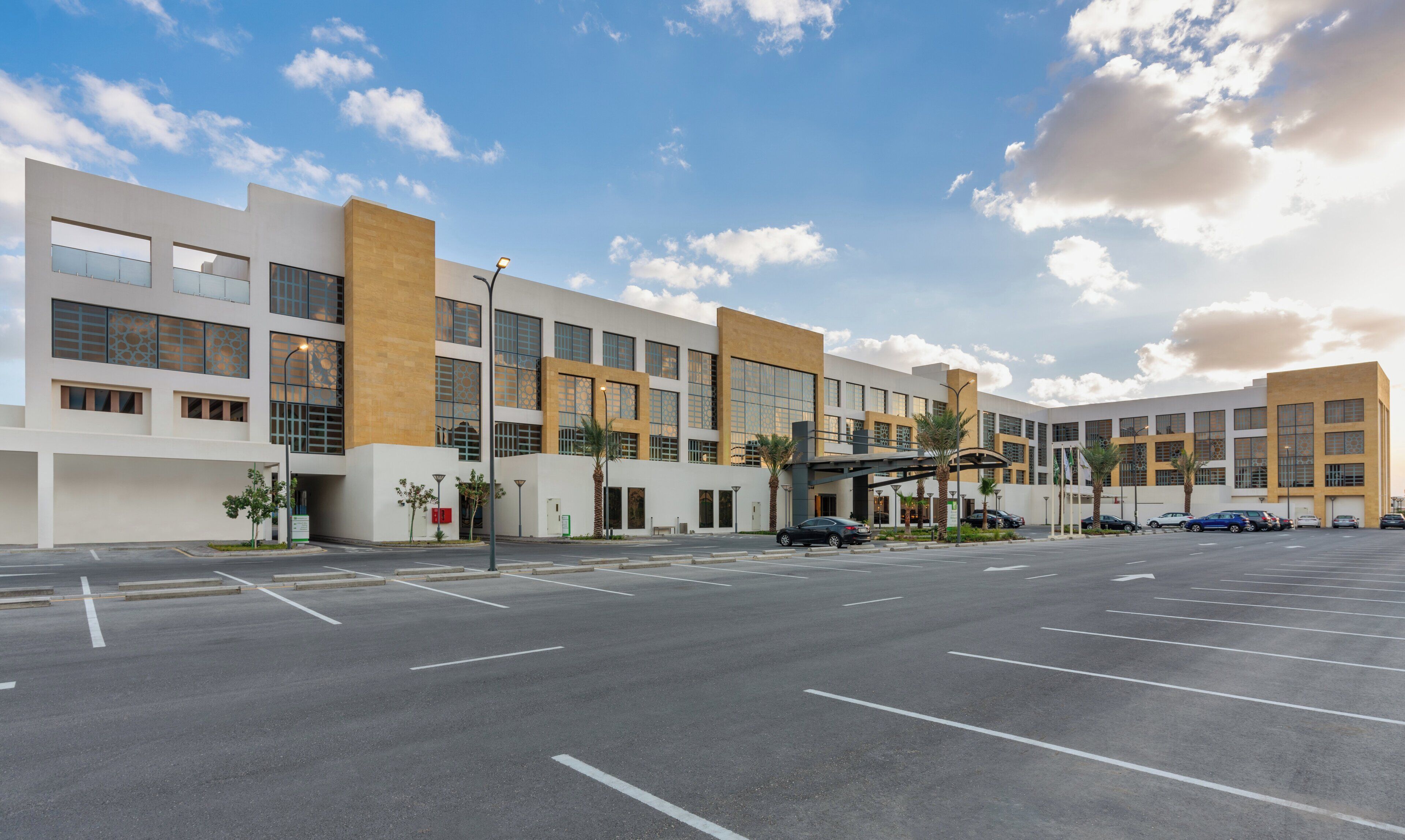 A modern hotel with a parking lot, multiple entry points, and a covered walkway.