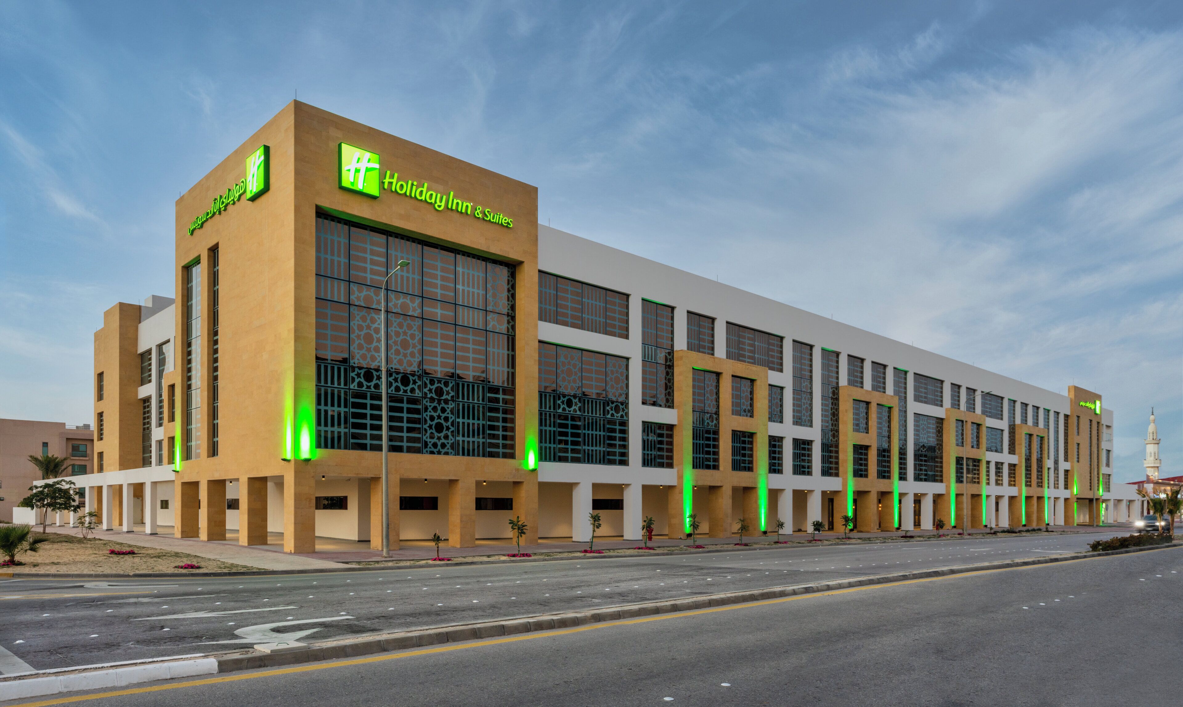 A modern Holiday Inn & Suites with a prominent entrance, large windows, and a clean facade.