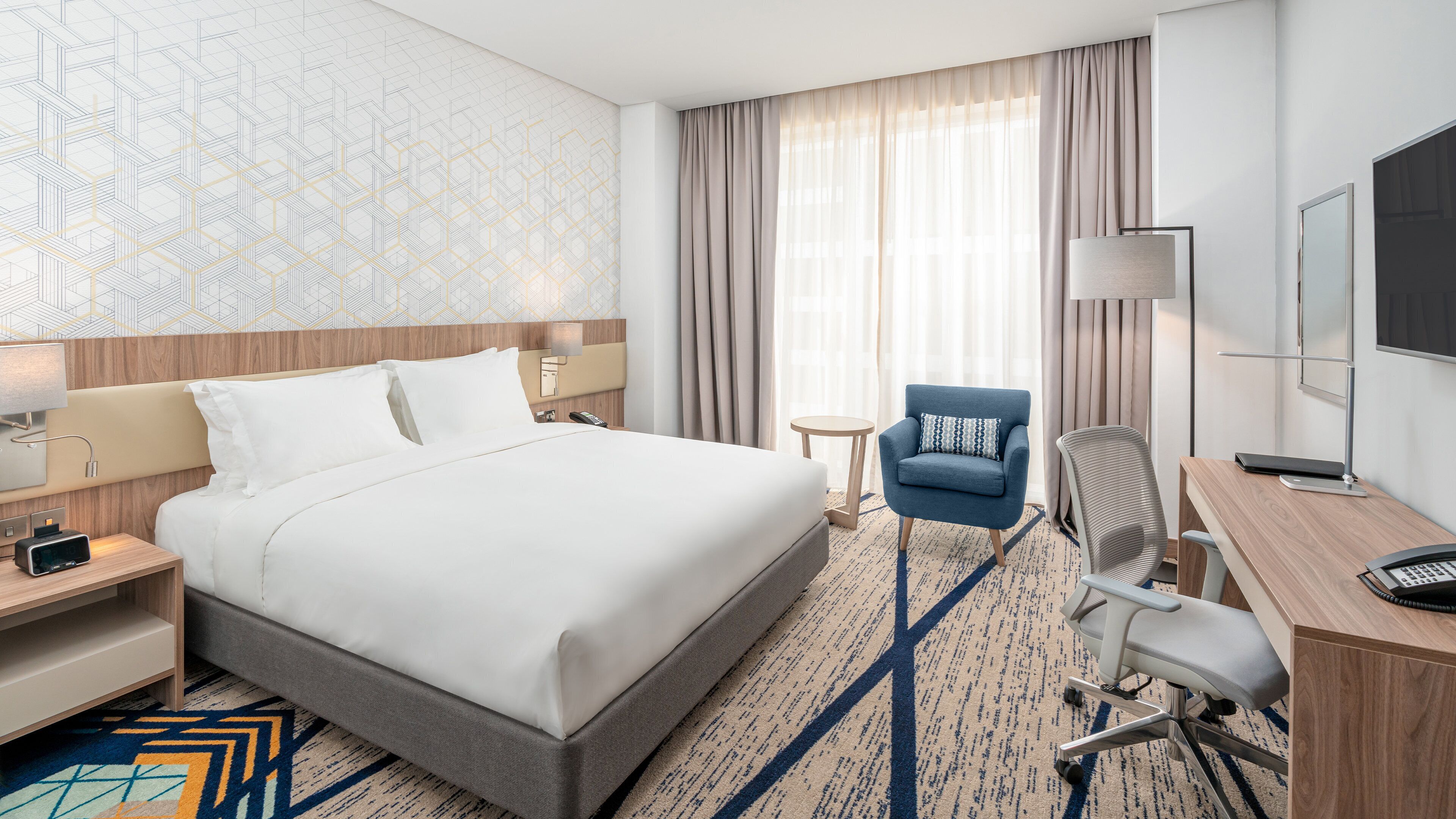 Una camera d'hotel con un letto grande, una scrivania con una sedia, un tavolino e una televisione.