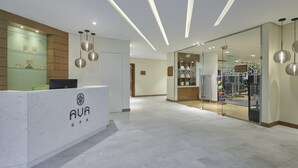 A modern spa reception area with a marble counter, pendant lighting, and a glass door leading to a gym. - Holiday Inn & Suites Al Jubail by IHG (Al Jubail)